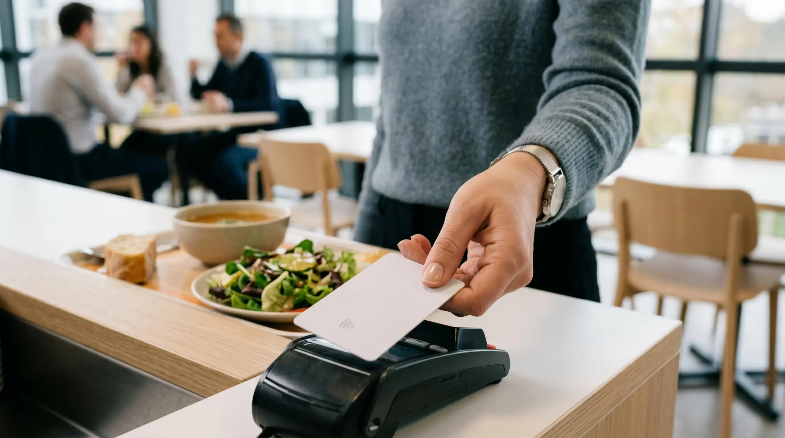 Carte avantages salariés tenue au-dessus d'un terminal de paiement dans une cafétéria d'entreprise moderne