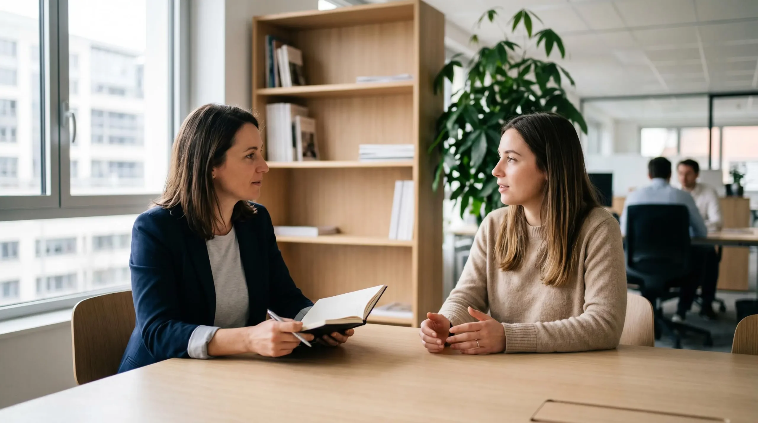 Manager et collaborateur en entretien individuel dans un bureau contemporain lumineux, assis à une table de réunion, discussion constructive dans une atmosphère sereine